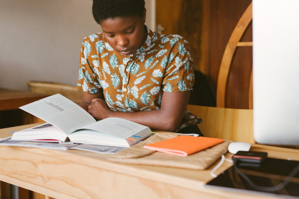 woman in brown dress with leaves on it reading a textbook