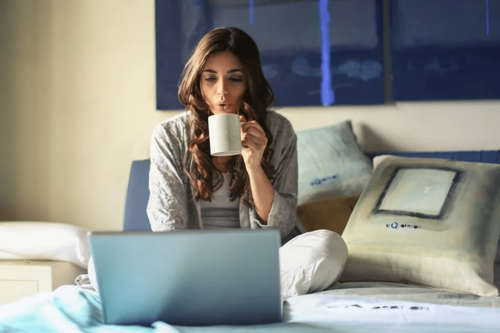 woman with a cup of coffee working on the bed